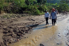 Đoàn công tác kiểm tra nguồn nước suối Bắc chảy qua điểm vỡ đập bể chứa bùn thải. (Ảnh: Tá Chuyên/TTXVN)
