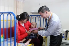Bác sỹ Pau Kieu Kong đang thăm khám cho bệnh nhi. (Ảnh: Hoàng Nhương/Vietnam+)
