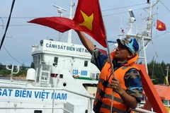 Chiến sỹ tàu Cảnh sát biển 9002 kéo cờ Tổ quốc, chuẩn bị xuất phát đi làm nhiệm vụ. (Ảnh: Đỗ Trưởng/TTXVN)