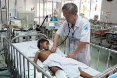 Bác sỹ Đặng Thanh Tuấn, Trưởng khoa Hồi sức ngoại thăm khám cho bệnh nhi. (Ảnh: Phương Vy/TTXVN)