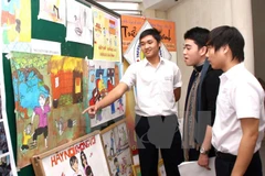 Học sinh tìm hiểu cách phòng chống bạo lực gia đình qua tranh ảnh. (Ảnh: Trần Lê Lâm/TTXVN)