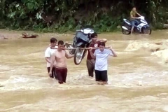 Người tham gia giao thông phải thuê người dân khênh xe máy qua các dập tràn đường ĐT 185 đoạn xã Xuân Vân, Kiến Thiết, huyện Yên Sơn với giá 50.000 đồng/lượt. (Ảnh: Quang Đán/TTXVN)