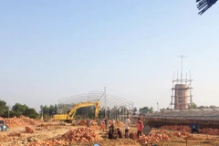 Hàng chục công nhân cùng máy móc vẫn hối hả làm việc, bất chấp việc công trình khuyết giấy phép. (Ảnh: PV/Vietnam+)