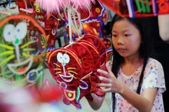 Các em thiếu nhi thích thú lựa chọn lồng đèn. (Ảnh: An Hiếu/TTXVN)