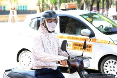 Người dân mặc áo chống nắng, bịt kín mặt khi ra đường. (Ảnh: Thành Đạt/TTXVN)