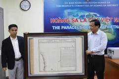 Anh Trần Thắng (bên trái) trao tặng tấm bản đồ Partie de la Cochinchine anh sưu tập được cho ông Võ Ngọc Đồng. Chủ tịch Ủy ban Nhân dân huyện Hoàng Sa. (Ảnh: Lê Lâm/Vietnam+)