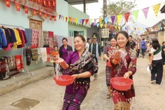 Những cô gái dân tộc Lào té nước cầu may. (Ảnh: Xuân Tư/TTXVN)