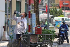 Một người dân bổ sung thêm nước khi phải di chuyển dưới cái nắng, nóng trên 40 độ C. (Ảnh: Hoàng Hiếu/TTXVN)