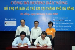 Đại diện Tổng đài 1022 và Trung tâm Cung cấp dịch vụ Công tác xã hội Đà Nẵng ký kết Quy chế phối hợp. (Ảnh: Trần Lê Lâm/TTXVN)