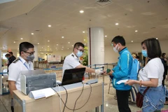 Nhân viên y tế kiểm tra phiếu khai báo y tế của hành khách trước khi làm thủ tục nhập cảnh tại cửa khẩu Sân bay quốc tế Nội Bài (Ảnh: TTXVN)