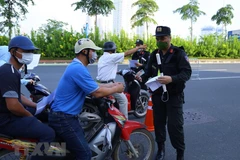 Lực lượng chức năng nhắc nhở người dân thực hiện nghiêm công tác phòng, chống dịch. (Ảnh: TTXVN)
