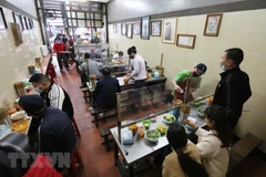 Quán ăn trong nhà lắp tấm chắn giữa các vị trí ngồi đảm bảo phòng chống dịch. (Ảnh: Thành Đạt/TTXVN)