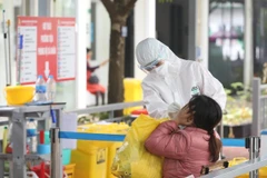 Nhân viên y tế bệnh viện Thanh Nhàn lấy mẫu xét nghiệm COVID-19 cho người đến khám có triệu chứng. (Ảnh: Minh Quyết/TTXVN)