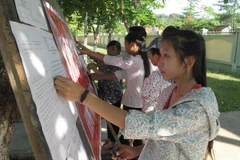 Các thí sinh xem thông báo và hướng dẫn kỳ thi tốt nghiệp Trung học phổ thông. (Ảnh: Nguyễn Văn Nhật/TTXVN)