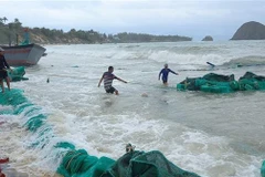 Ngư dân xã An Hòa Hải trục vớt tàu bị sóng đánh chìm lên bờ để sữa chữa. (Ảnh: Xuân Triệu/TTXVN)