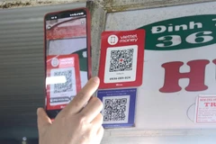 Khách hàng quét mã QR-code khi mua sắm tại chợ Cồn. (Ảnh: Quốc Dũng/TTXVN)