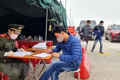 Lực lượng chức năng làm nhiệm vụ hướng dẫn, phân luồng giao thông, khai báo y tế tại chốt trạm cầu Bạch Đằng, thị xã Quảng Yên. (Ảnh: TTXVN)