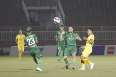 Pha tranh bóng giữa các cầu thủ đội chủ nhà Sài Gòn FC (áo xanh) và SLNA (áo vàng). (Ảnh: Thanh Vũ/TTXVN)