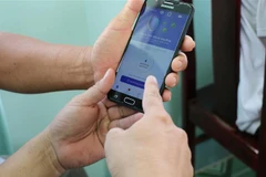 Hướng dẫn người dân cài đặt ứng dụng Bluezone trên thiết bị điện thoại thông minh để phòng chống dịch bệnh COVID-19. (Ảnh: Chương Đài/TTXVN)