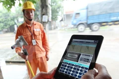 Công nhân Công ty Điện lực Sóc Sơn thuộc Tổng Công ty Điện lực Hà Nội ghi chỉ số côngtơ khách hàng trên địa bàn bằng thiết bị mới. (Ảnh: Ngọc Hà/TTXVN)