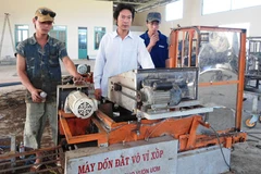 Nhà nông sáng chế Nguyễn Hồng Chương (áo trắng) trong xưởng cơ khí của mình. (Nguồn: Báo Lâm Đồng)