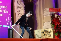 Tiết mục biểu diễn ảo thuật đâm xuyên người nằm trong thùng. (Ảnh: Gia Thuận/TTXVN)