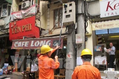 Nhân viên Công ty Điện lực Hoàn Kiếm đang ghi chỉ số công tơ cho khách hàng (Ảnh: Đức Duy/Vietnam+)