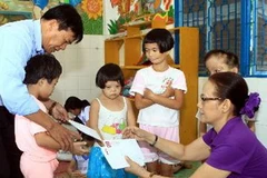 Đại diện Quỹ "Vì nỗi đau da cam " của TTXVN tổ chức thăm hỏi, tặng quà cho 10 trẻ em nhiễm chất độc da cam/dioxin. (Ảnh: TTXVN) 