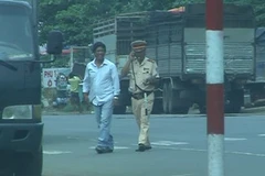 Chiến sĩ CSGT thuộc Trạm kiểm soát giao thông Suối Tre đứng giữa đường nghe điện thoại khi làm nhiệm vụ. (Nguồn: Sỹ Tuyên/Vietnam+)
