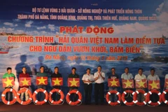 Lãnh đạo Quân chủng Hải quân và Bộ Tư lệnh Vùng 3 Hải quân tặng cờ Tổ quốc, phao cứu sinh cho ngư dân tại chương trình. (Ảnh: Nguyễn Sơn/TTXVN)
