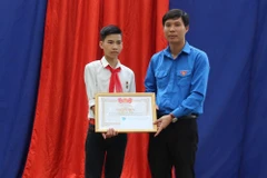 Phó Bí thư Tỉnh đoàn Thanh Hóa Nguyễn Hữu Tuất trao Giấy khen của Hội đồng đội tỉnh cho em Vũ Văn Hùng. (Ảnh: Nguyễn Nam/TTXVN)