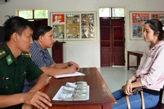 Cán bộ Đồn Biên phòng Vĩnh Ngươn làm việc với đối tượng Phan Thị Hoài Phương. (Ảnh: Công Mạo/TTXVN)