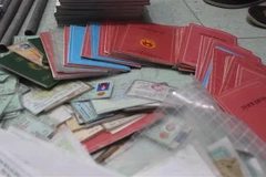  Lực lượng công an thu giữ nhiều sổ hộ khẩu, chứng minh nhân dân liên quan đến hoạt động tín dụng đen. (Ảnh: Công Phong/TTXVN)