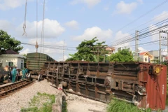 Lực lượng cứu hộ khắc phục sự cố tàu hàng trật bánh và di chuyển toa tàu khỏi hiện trường. (Ảnh: Văn Đạt/TTXVN)