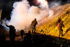 Người di cư bỏ chạy để tránh đạn hơi cay. (Nguồn: AFP)