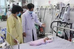 Bác sỹ Dương Thanh Tùng, Khoa Hồi sức tích cực (Bệnh viện Sản-Nhi tỉnh An Giang) thăm khám cho bệnh nhi. (Ảnh: Thanh Sang/TTXVN)