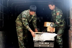 Cán bộ, chiến sỹ Đồn Biên phòng Vĩnh Nguơn kiểm đếm và vận chuyển tang vật buôn lậu hàng hóa vào kho tạm giữ. (Ảnh: Công Mạo/TTXVN)