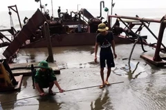 Bộ đội biên phòng Đồn Biên phòng Long Hòa đo kiểm tra lượng cát trái phép trên sà lan 3326 bị thu giữ. (Ảnh: TTXVN)