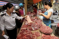 Nhân viên thú y kiểm tra hộ kinh doanh thịt lợn tại chợ. (Ảnh: Vũ Sinh/TTXVN)