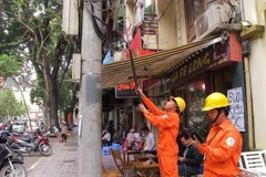 Nhân viên ngành điện đang chốt chỉ số công tơ của khách hàng. (Ảnh: Đức Duy/Vietnam+)