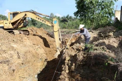 Ngành chức năng đào sâu để tìm ống thải ngầm. (Ảnh: Công Phong/TTXVN)