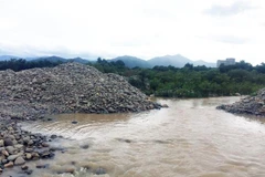Nhiều đống đá lớn đã được doanh nghiệp khai thác, tập kết đã cản trở dòng chảy của sông Dinh. (Ảnh: Công Thử/TTXVN)