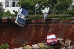 Một người đàn ông ở Hải Khẩu, tỉnh Hải Nam, Trung Quốc nhìn vào chiếc xe bị mắc kẹt trong 'hố tử thần' với ánh mắt vô vọng. (Nguồn: Reuters)