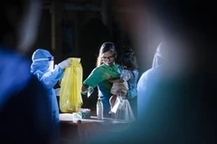 Các công dân thực hiện sát khuẩn, thay khẩu trang và nhận đồ dùng sinh hoạt trước khi vào phòng cách ly theo dõi COVID-19. (Ảnh: Trọng Đạt/TTXVN)