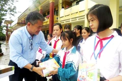 Các nhà hảo tâm trao tặng tập vở cho học sinh vùng lũ xã An Ninh, huyện Quảng Ninh. (Ảnh: Võ Dung/TTXVN)