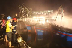Lực lượng chữa cháy nỗ lực dập lửa trên tàu cá. (Ảnh: Nguyễn Oanh/TTXVN)