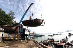 Xe cần cẩu đưa các phương tiện đánh bắt thủy sản của ngư dân Đà Nẵng lên bờ, vận chuyển vào sâu đất liền để tránh bão số 9. (Ảnh: Trần Lê Lâm/TTXVN)