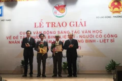 Bộ trưởng Bộ Lao động-Thương binh và Xã hội Đào Ngọc Dung trao giải cho các tác giải đoạt giải Nhất. (Ảnh: PV/Vietnam+)