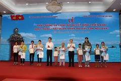 Trao quà cho các con ngư dân được nhận đỡ đầu. (Ảnh: Minh Trí/TTXVN)