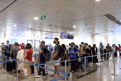 Hành khách xếp hàng vào khu vực soi chiếu kiểm tra an ninh. (Ảnh: Tiến Lực/TTXVN)